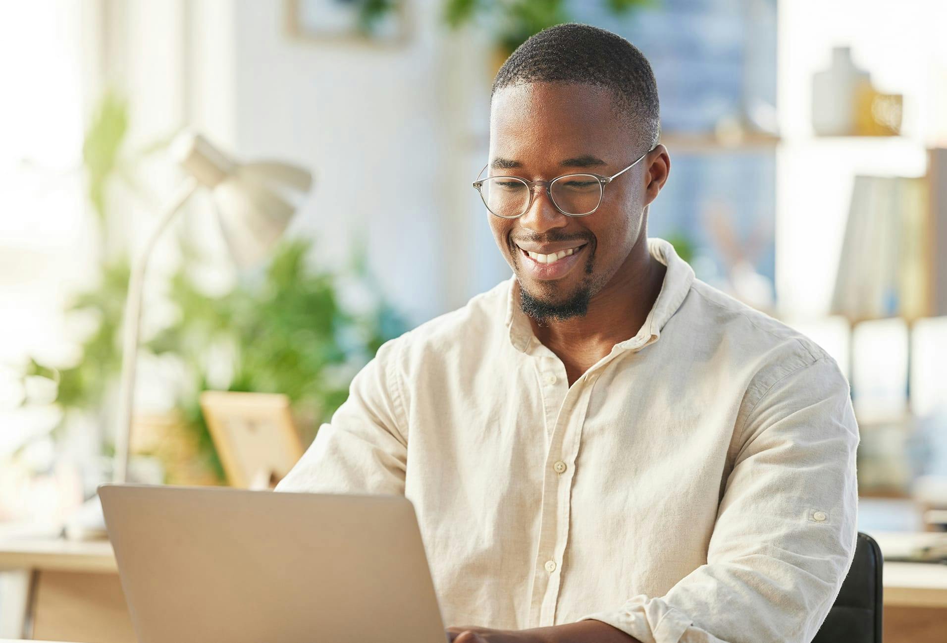 Man smiling at desk while using laptop