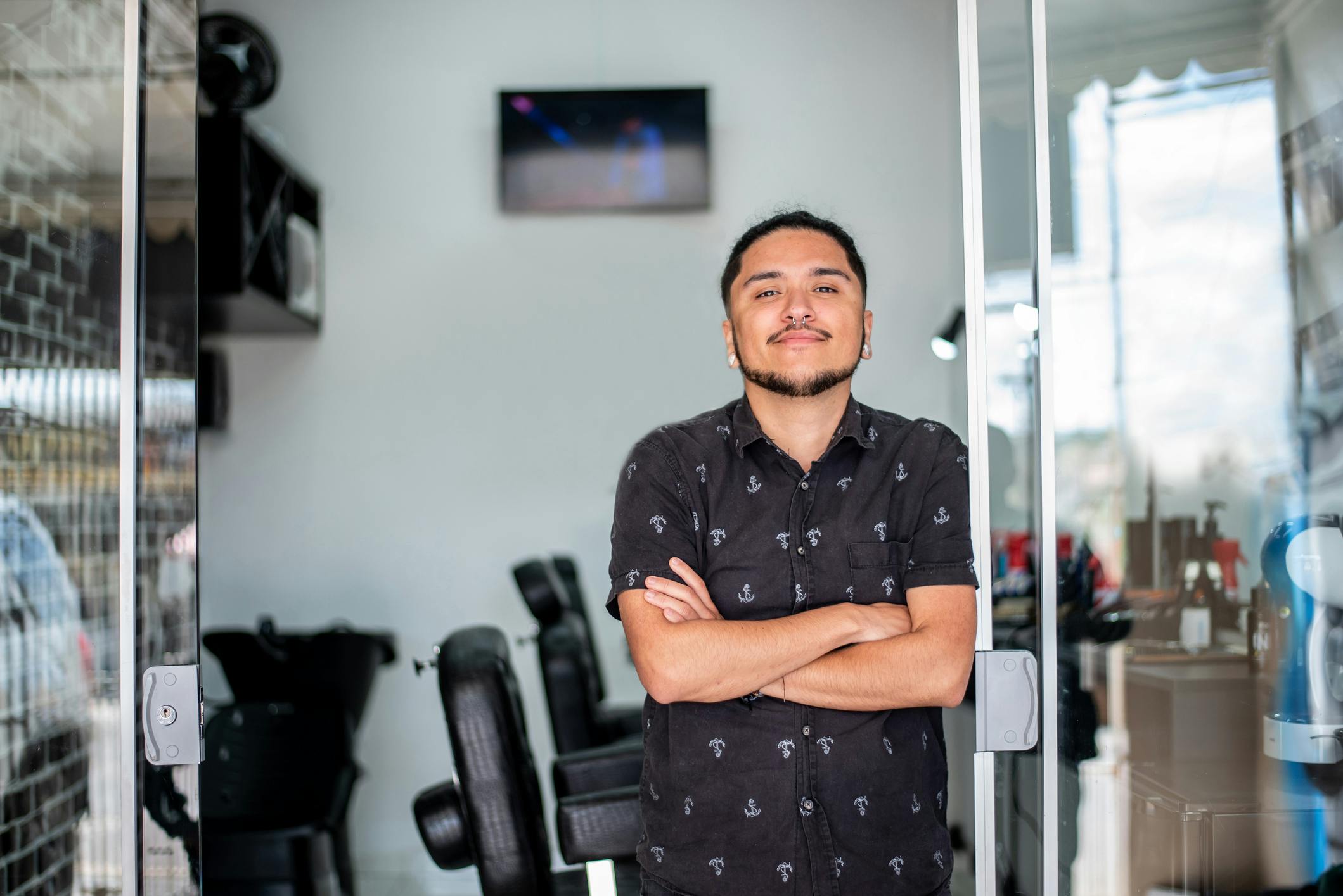 man standing in a barber shop with his arms crossed