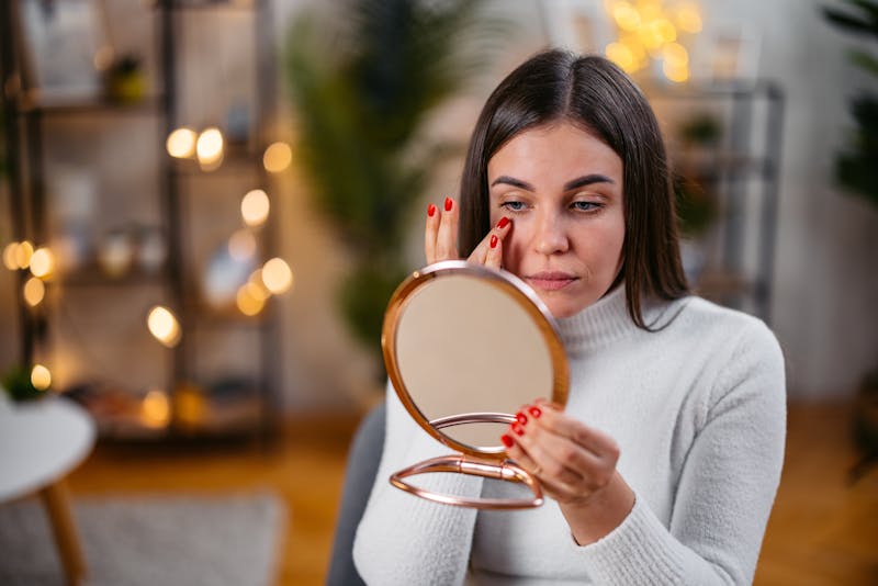 woman examining her under eyes