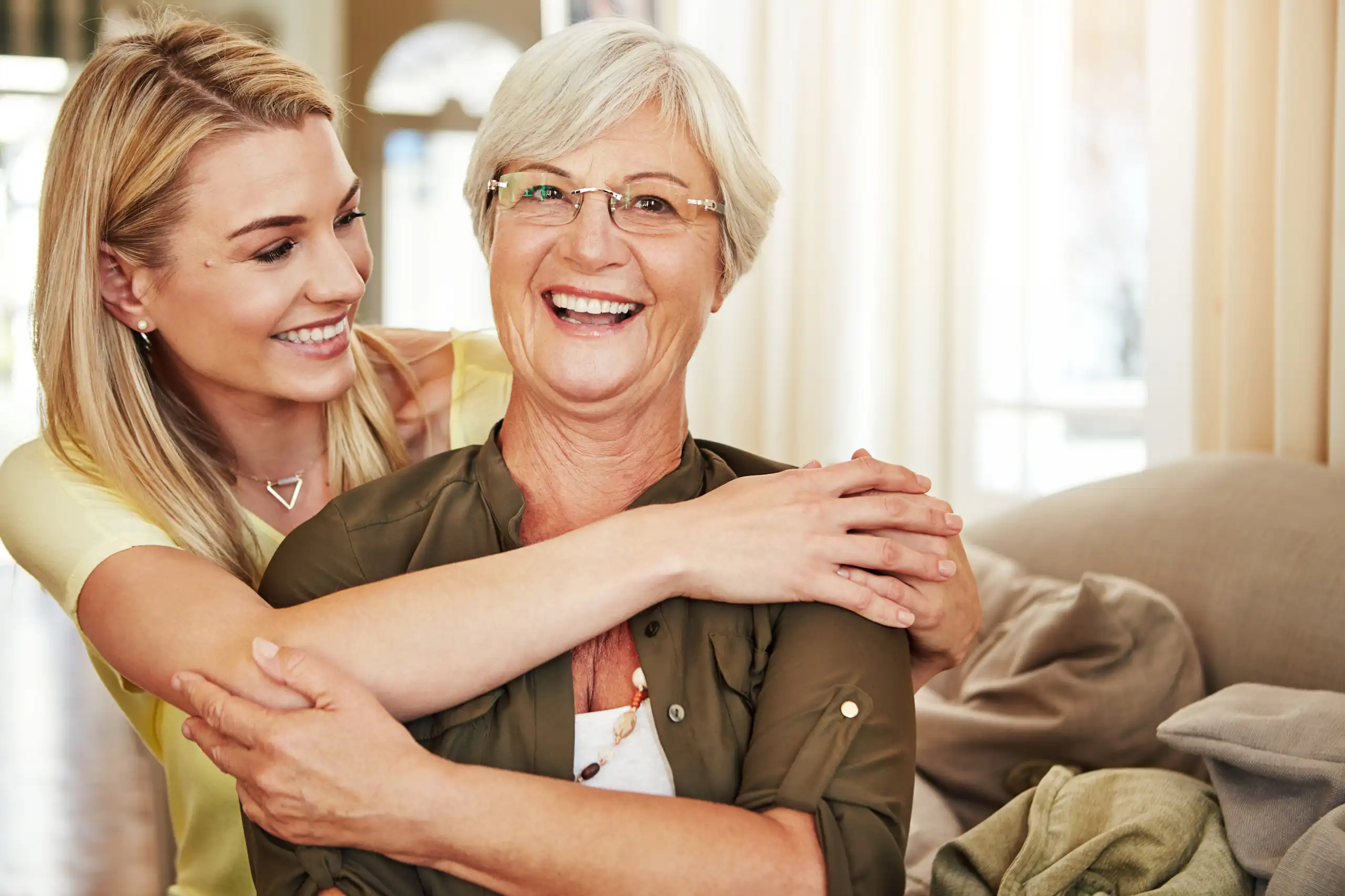 Adult daughter embracing her smiling mother in a warm, affectionate moment at home