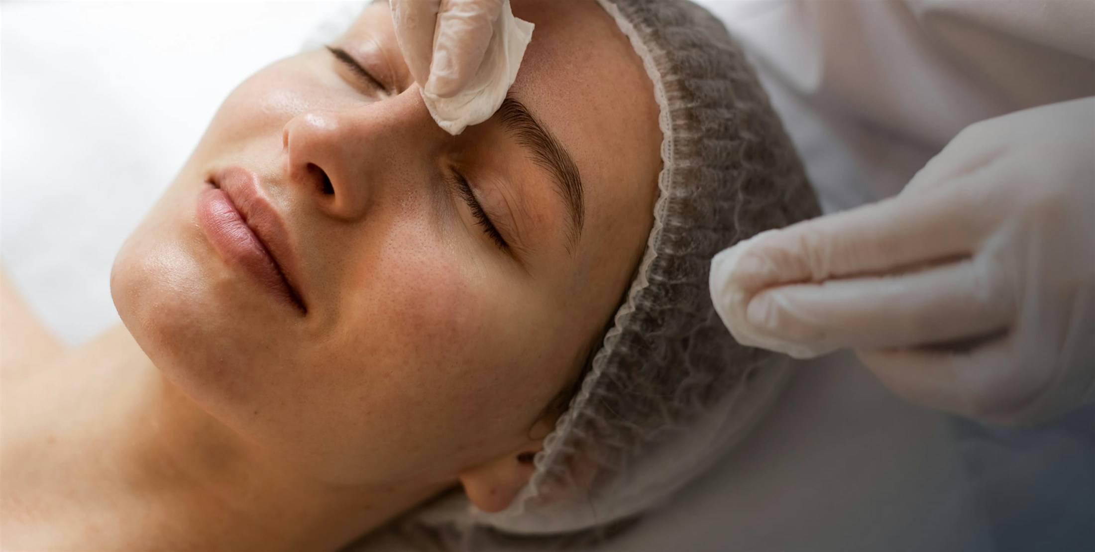 Woman having face cleansed by physician