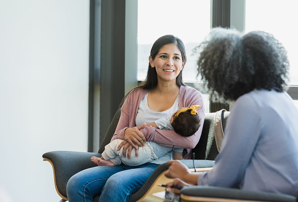 woman holding a baby in her arms while sitting in a chair