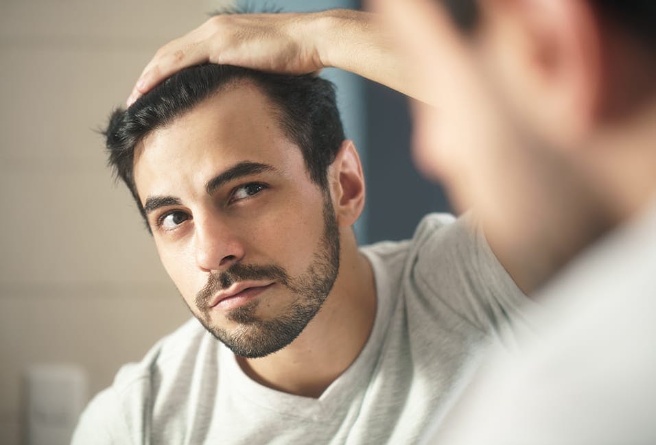 man looking in the mirror at his hair