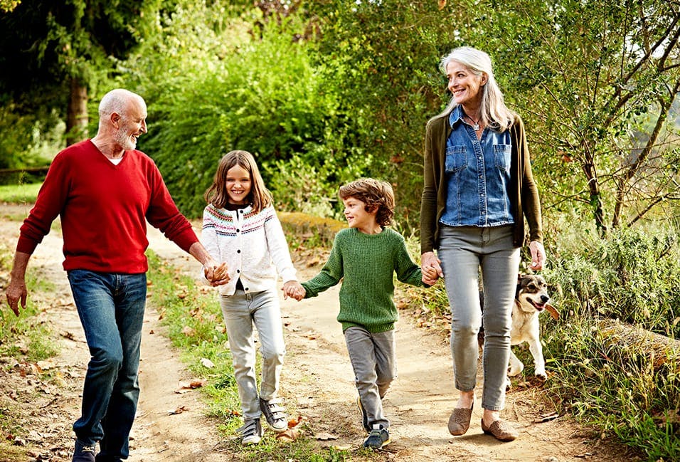 Middle-aged couple smiling as they walk with their two young children