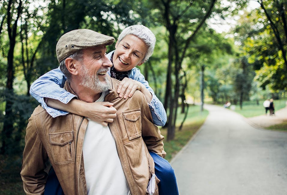 Man giving a woman a piggyback ride and smiling at each other