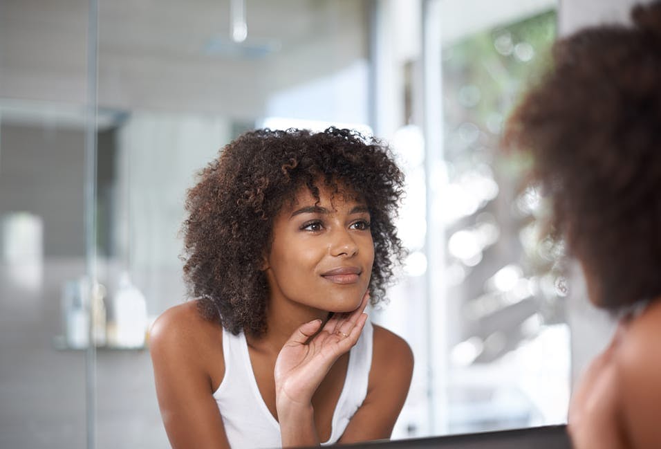 a woman looking at her reflection in the mirror