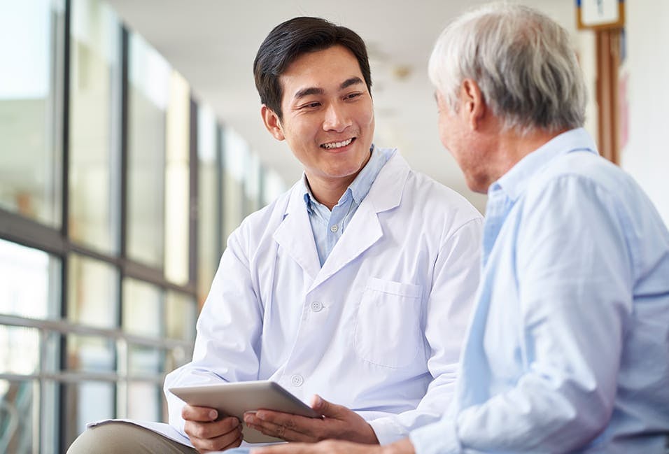 Male physician smiling at an older patient