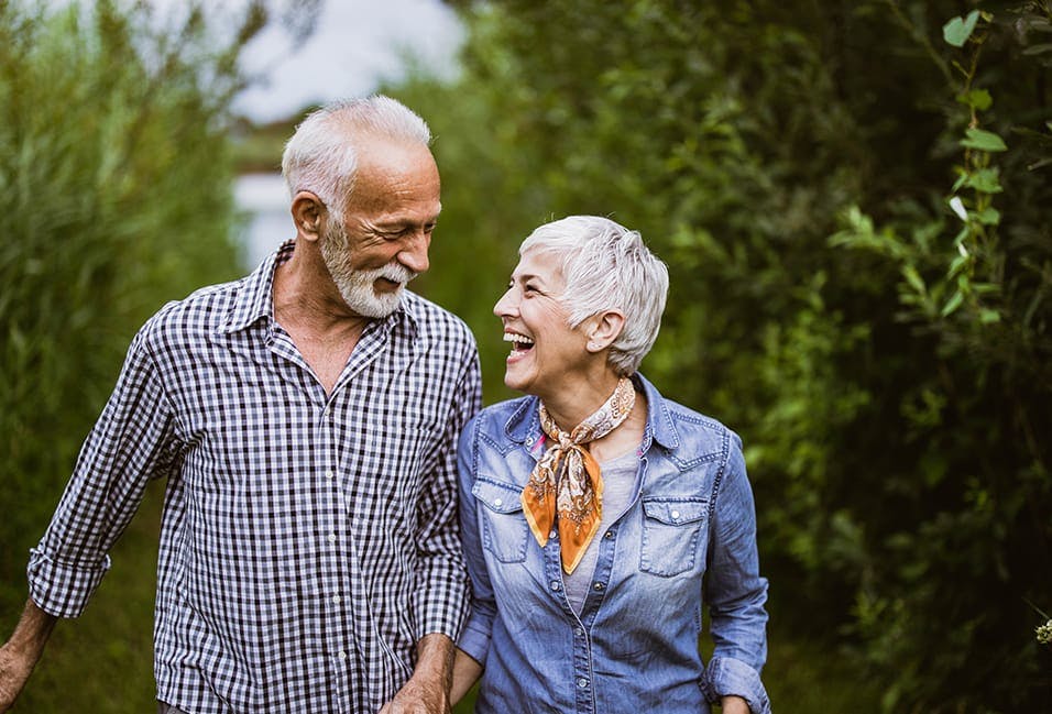 Older couple smiling at each other while standing outside