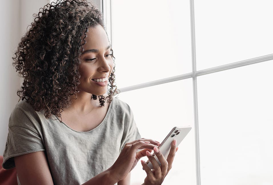 Young woman smiling while looking at her phone