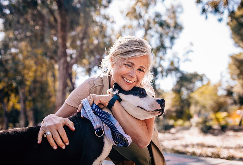 Older woman smiling and hugging a dog