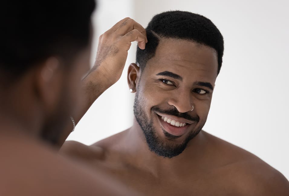 Man looking at his hair and face in the mirror
