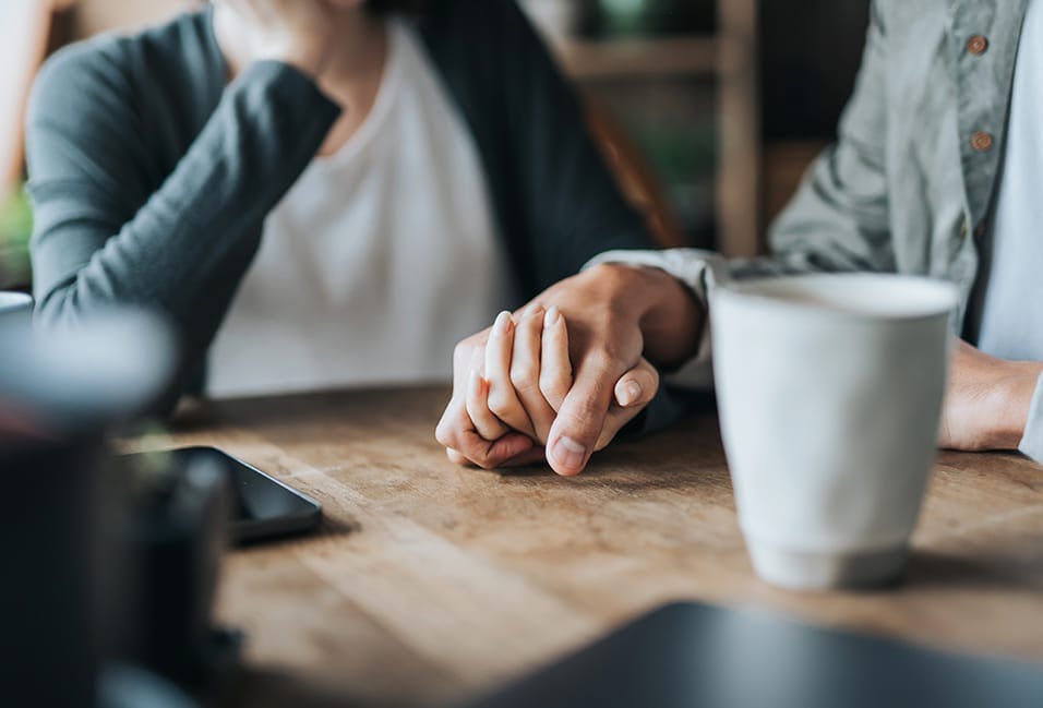 Couple holding hands on a tabletop