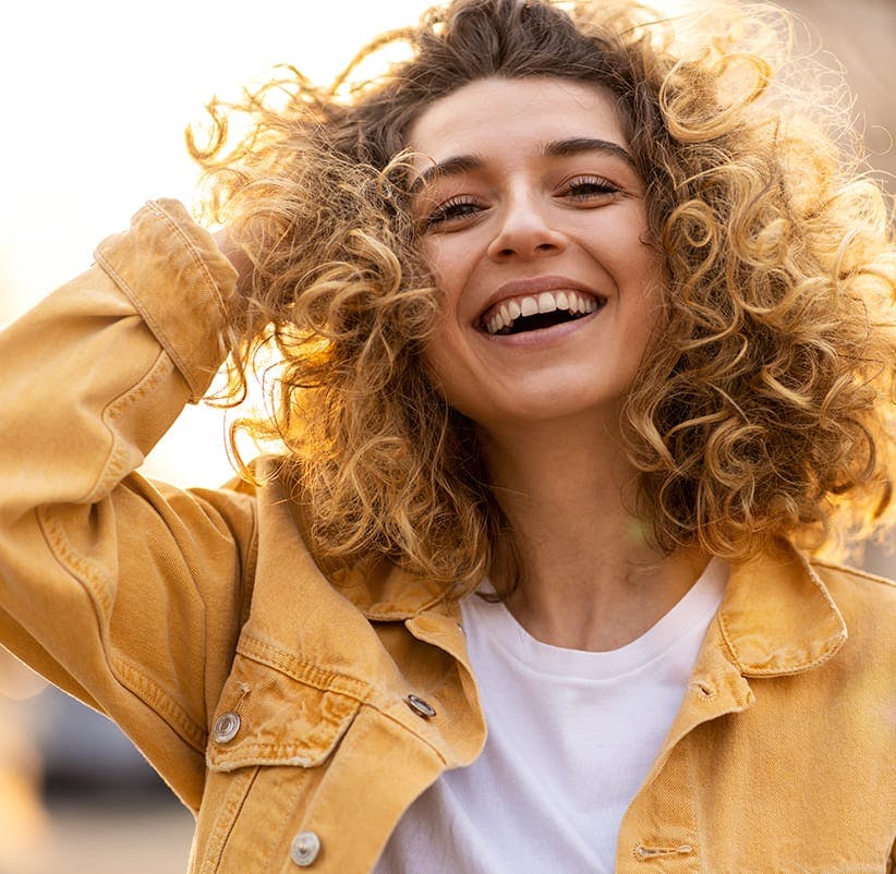 smiling woman with curly hair and yellow jacket