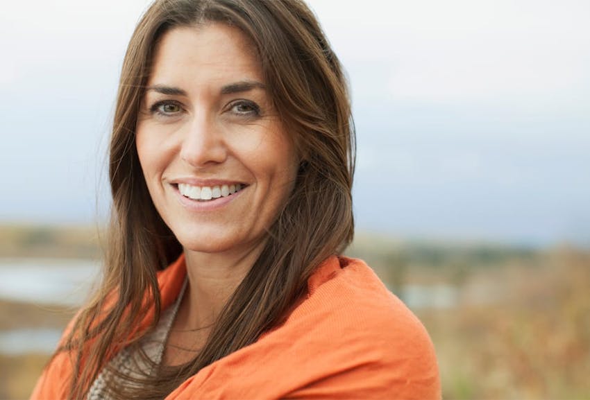 smiling woman with long brown hair and orange shirt