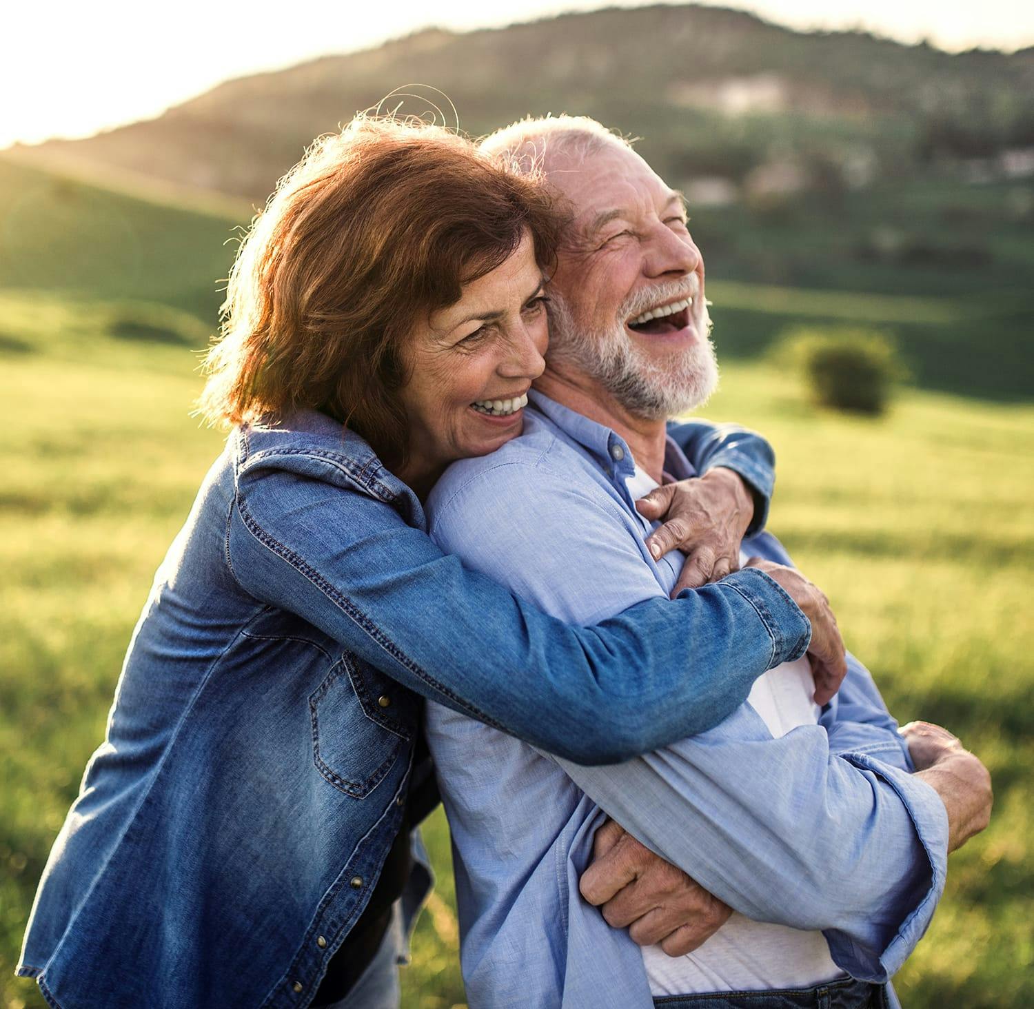 smiling older couple hugging each other in a field