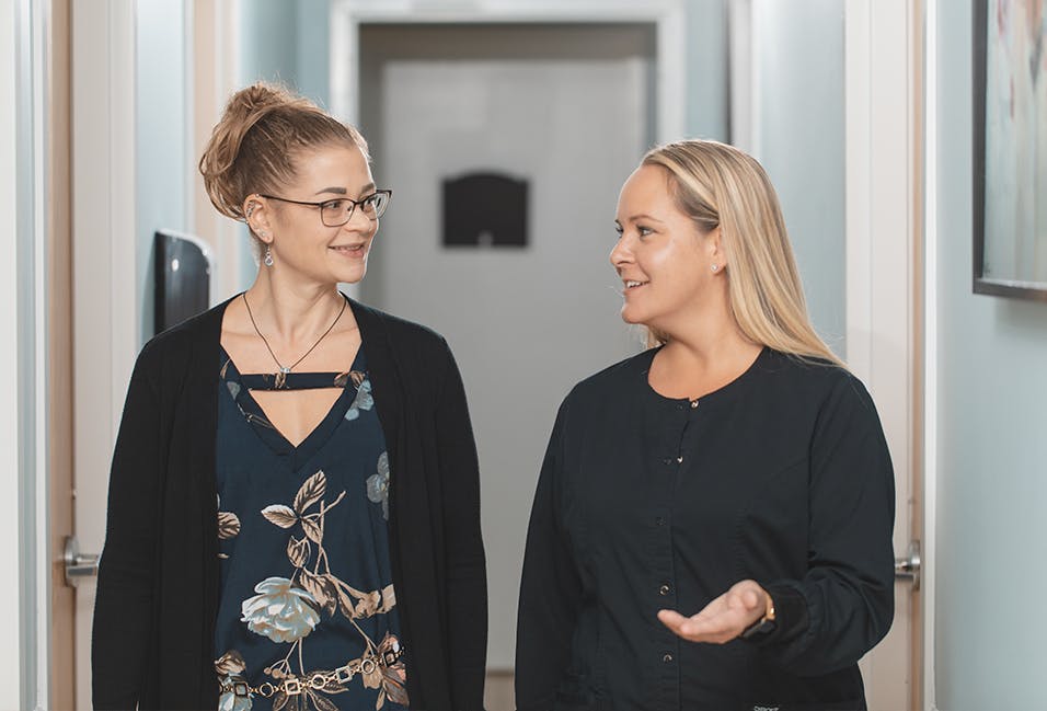 two women standing in a hallway talking to each other