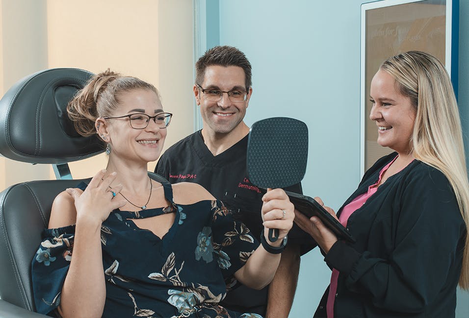 Dermatologist and patient care coordinator meeting with smiling dermatology patient