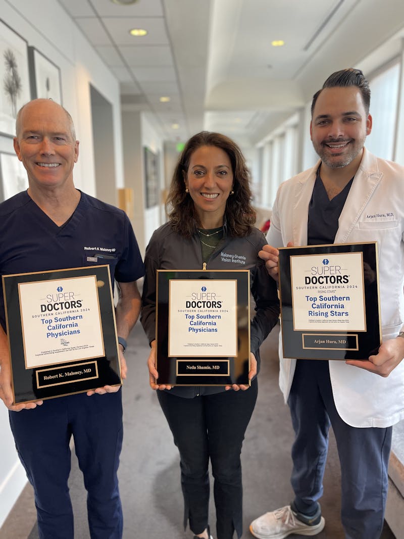 three doctors holding plaques in a hallway with a man and woman