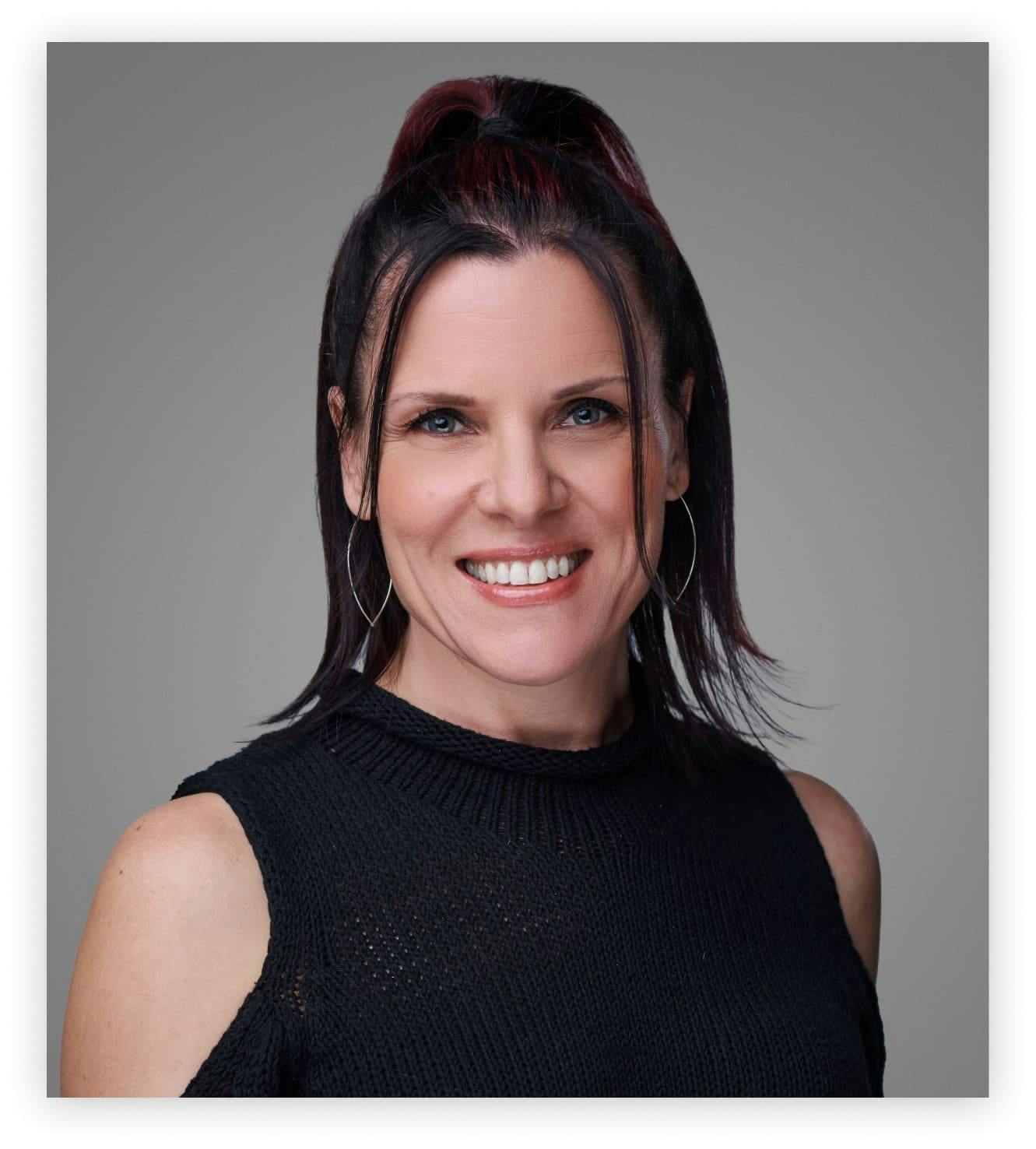 smiling Dr. Lucy Hostetter with black top and red hair up in pony tail