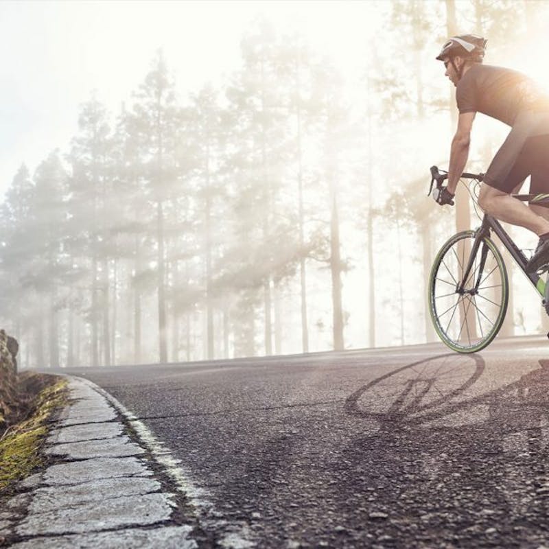 man riding a bike on a road in the middle of the woods