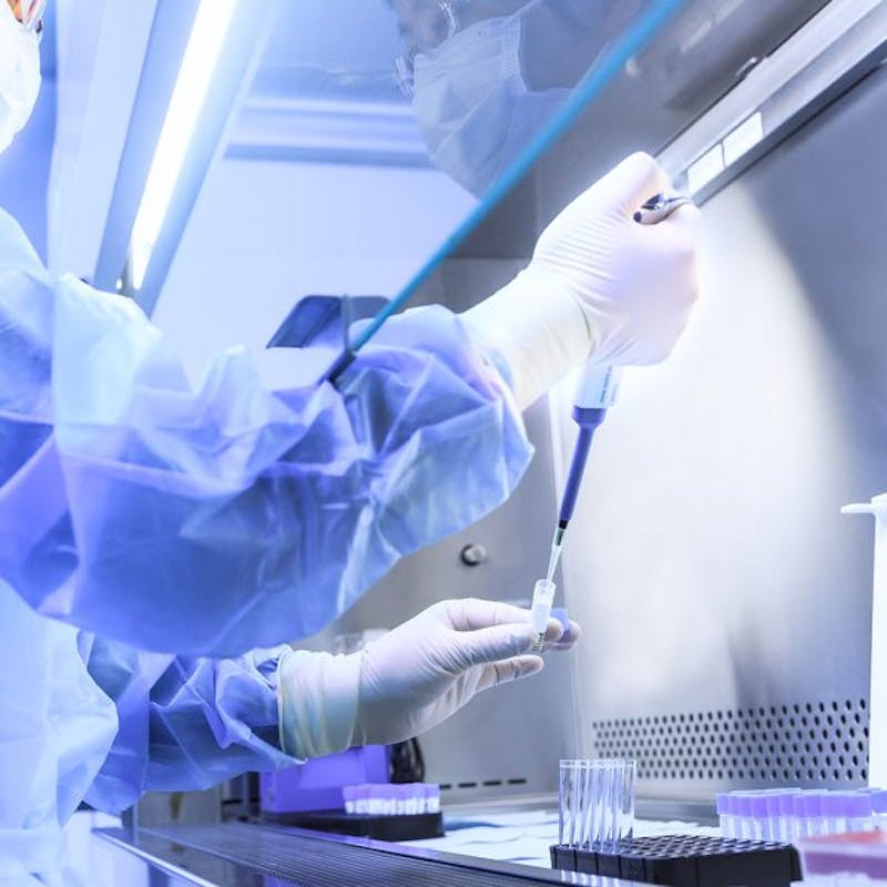 scientist in a lab coat and gloves holding a pipe