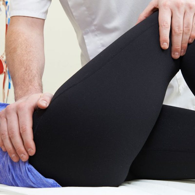 man in a white button up shirt is holding a patients leg to adjust it