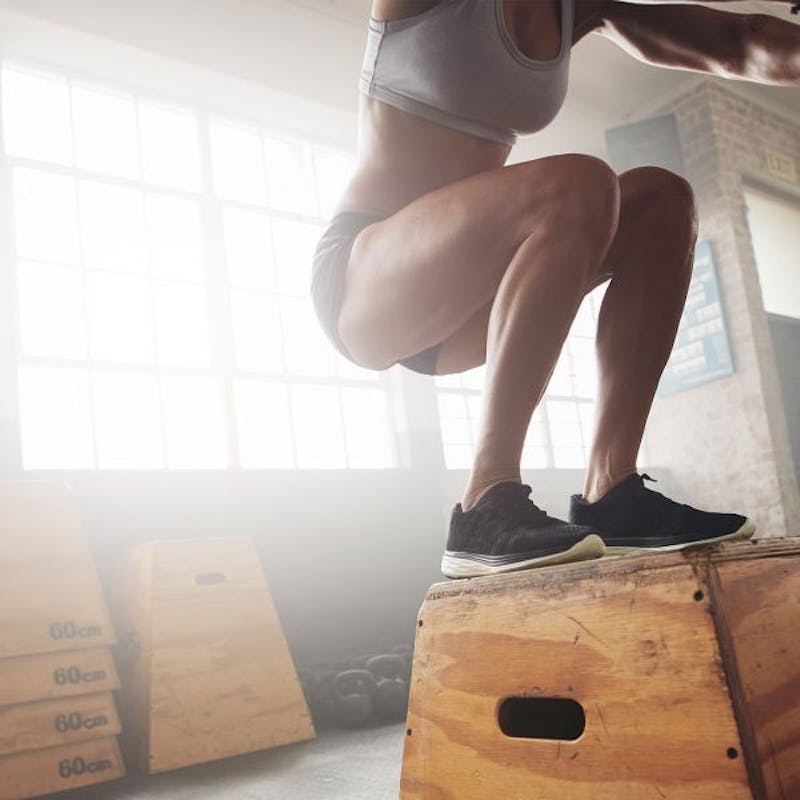 woman jumping on a box in a gym