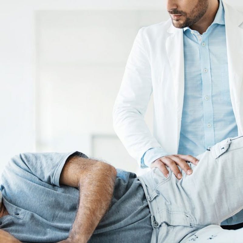 man lying on a bed with a doctor examining him