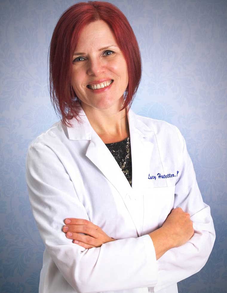 Dr. Lucy Hostetter in a lab coat smiling with her arms crossed