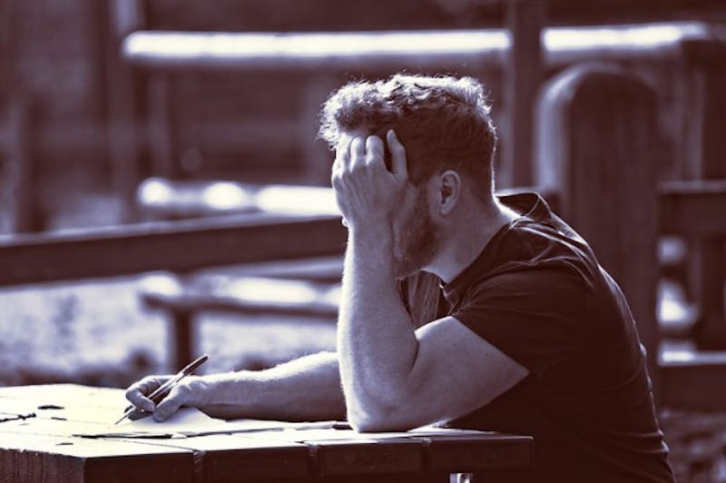 man sitting at a table with his hand on his face
