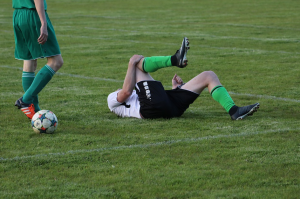 soccer player laying on ground in pain holding knee