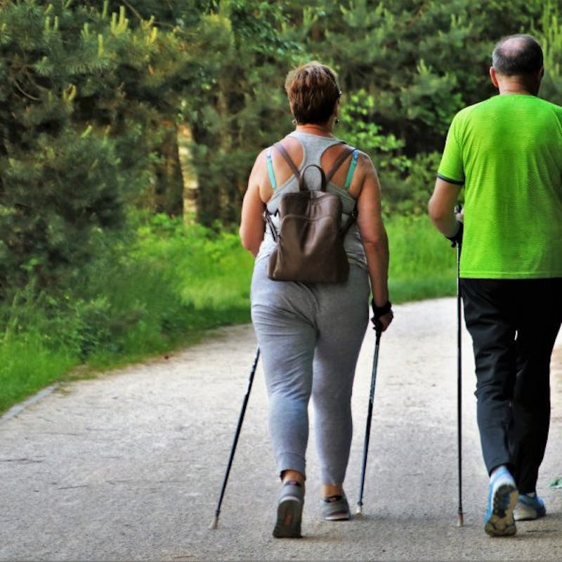 there are two people walking down a path with ski poles