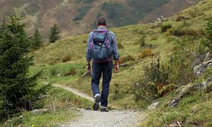 man hiking down trail in woods