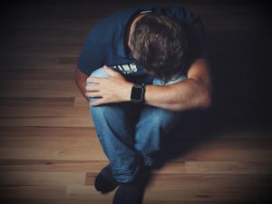 man sitting on floor with head on knees