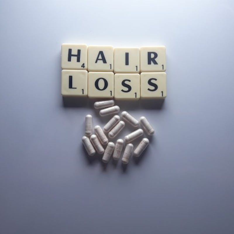 a close up of a pile of pills and a block with the word hair loss