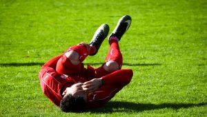 soccer player laying on ground in knee pain