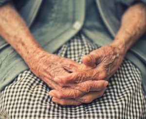 older person holding hands together on lap