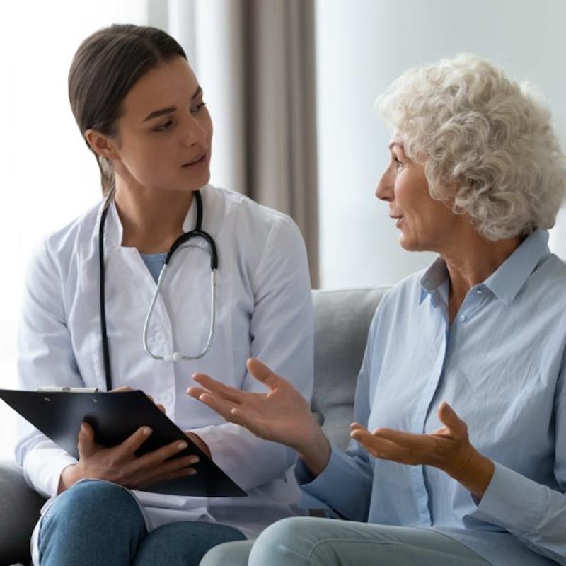a woman talking to a doctor while sitting on a couch