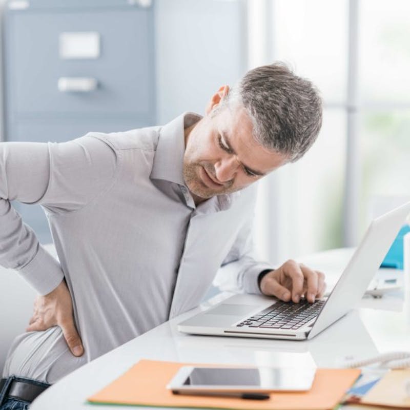 close up of man with back pain in office