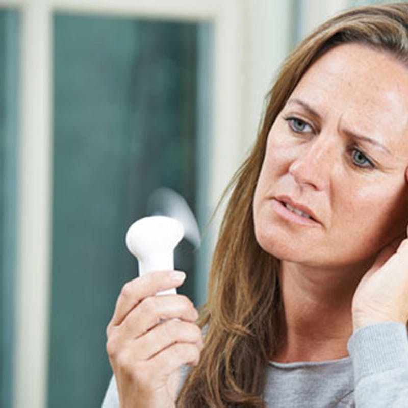 close up of woman cooling down with hand fan