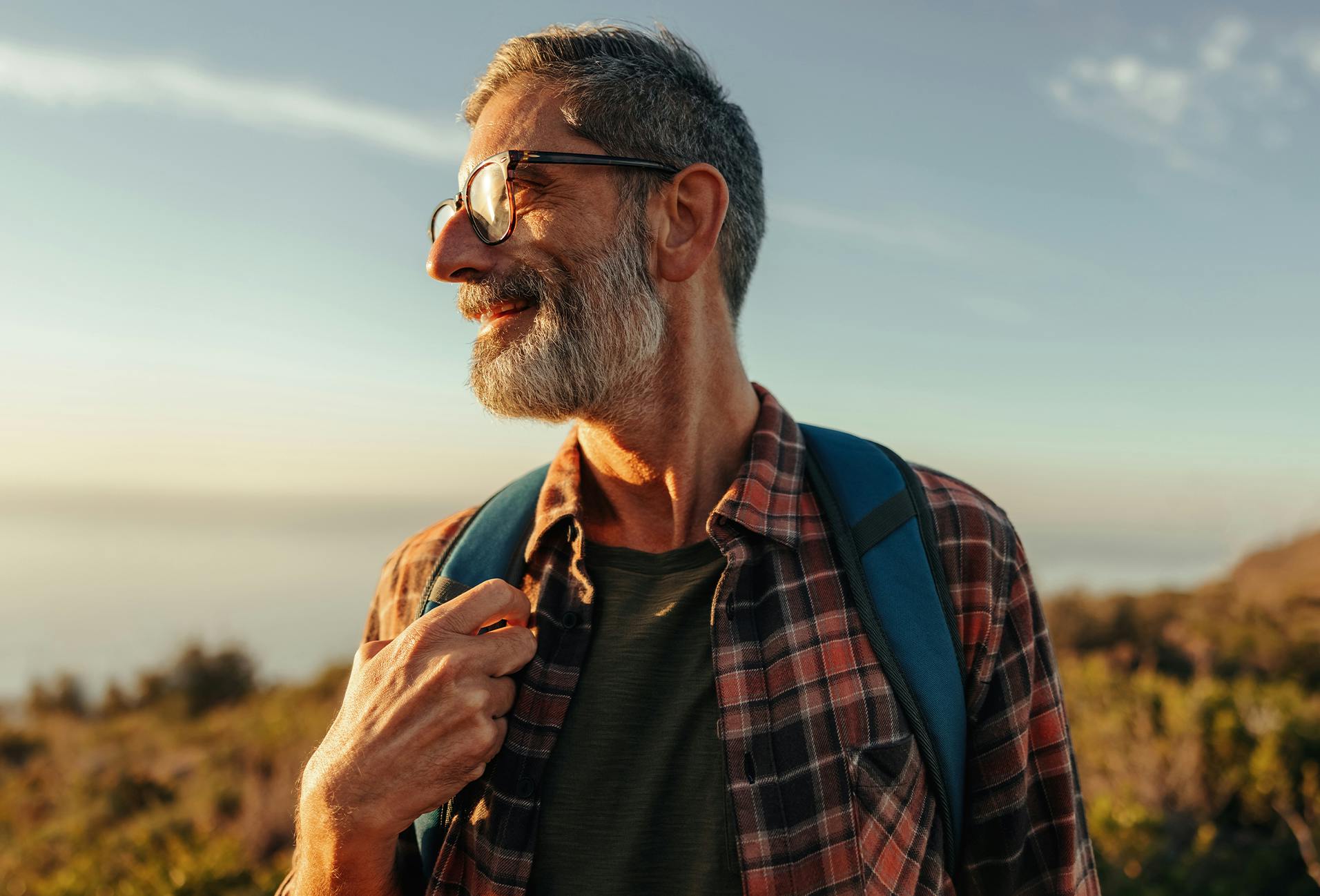 there is a man with a beard and glasses standing on a hill