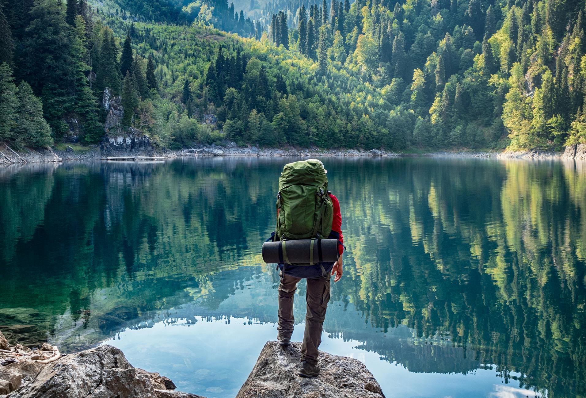 there is a man standing on a rock looking out at a lake