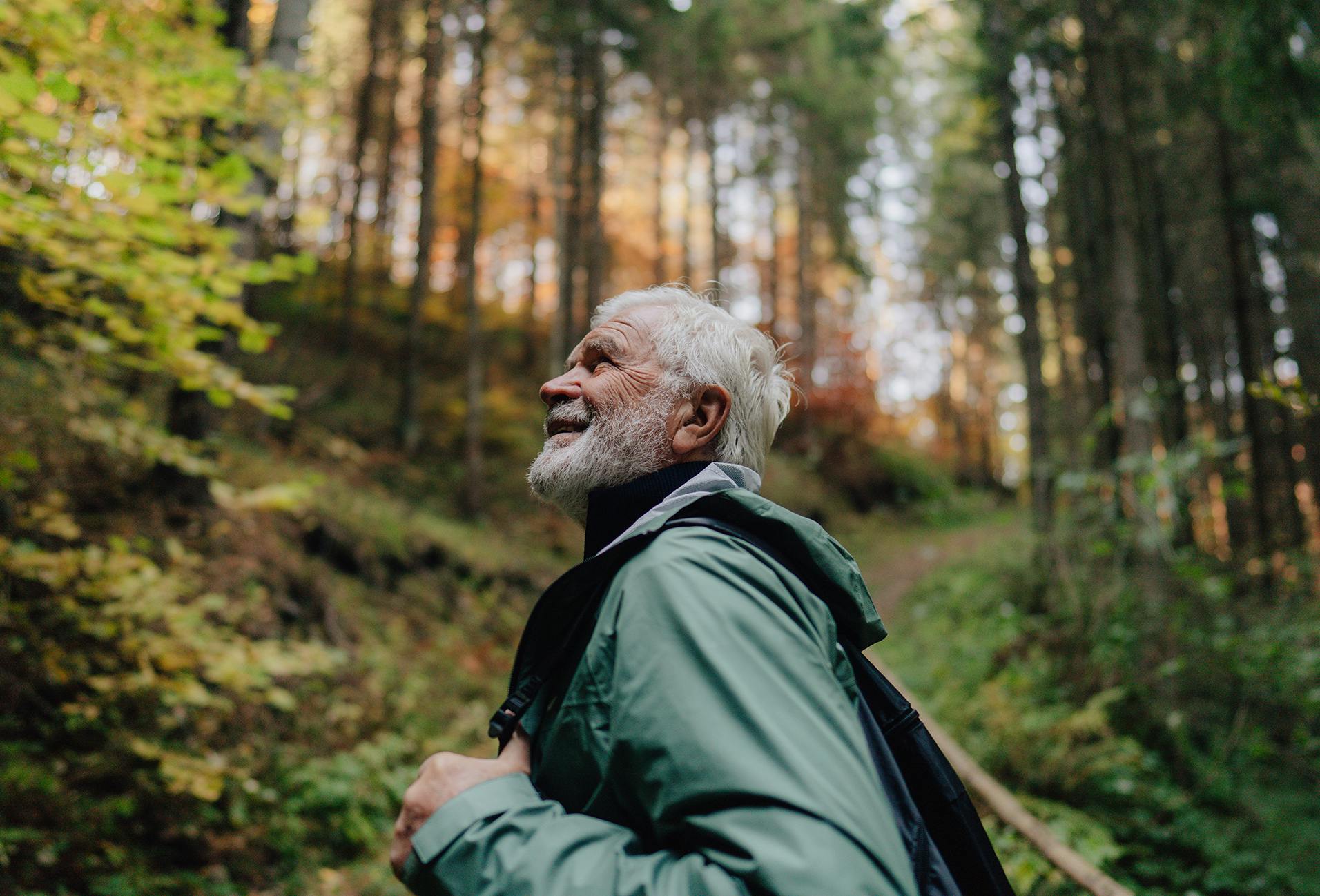 there is a man with a beard and a backpack walking in the woods