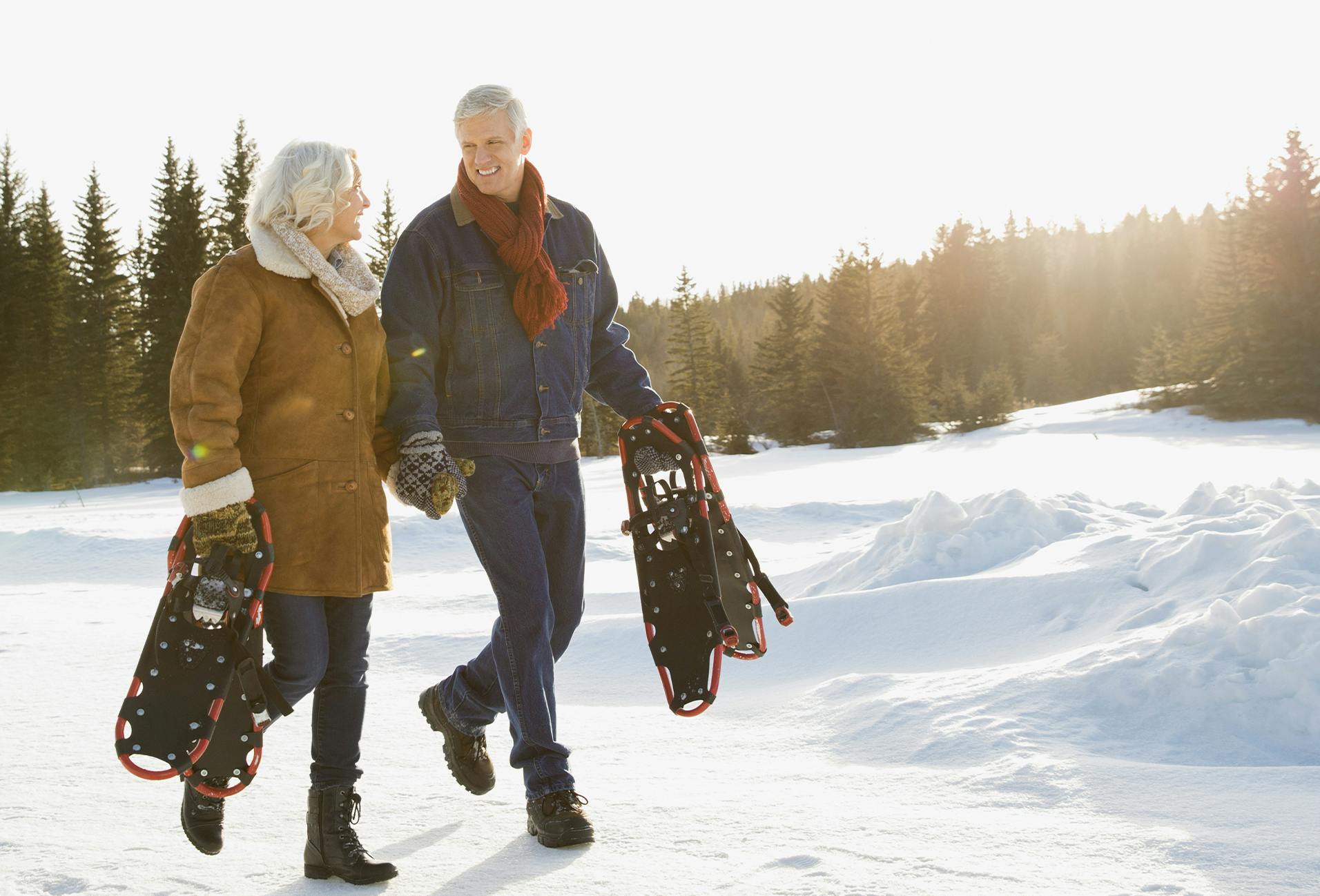 they are walking in the snow with their snowshoes in their hands