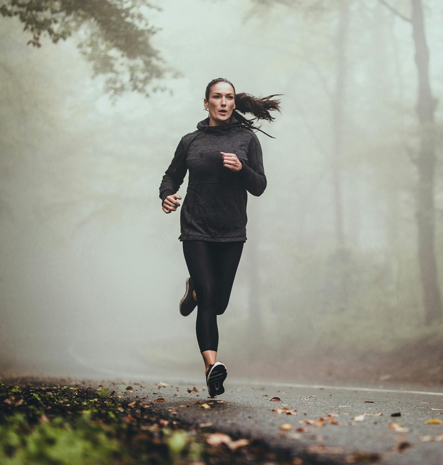 woman running in the foggy woods on a foggy day