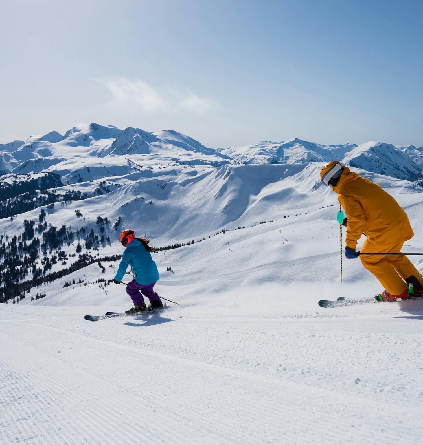 skiers on a mountain slope with mountains in the background