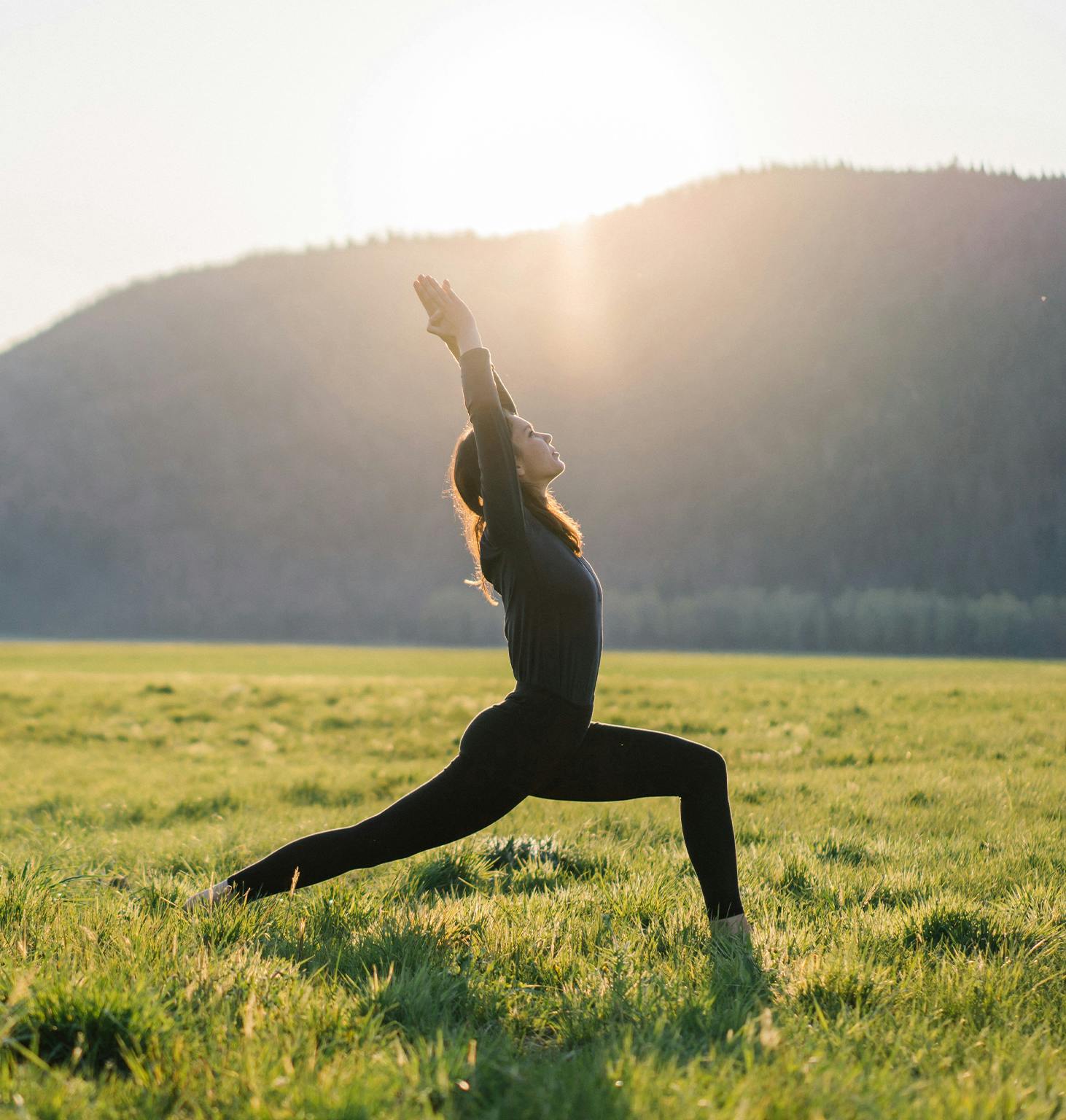 woman in a black outfit doing yoga in a field