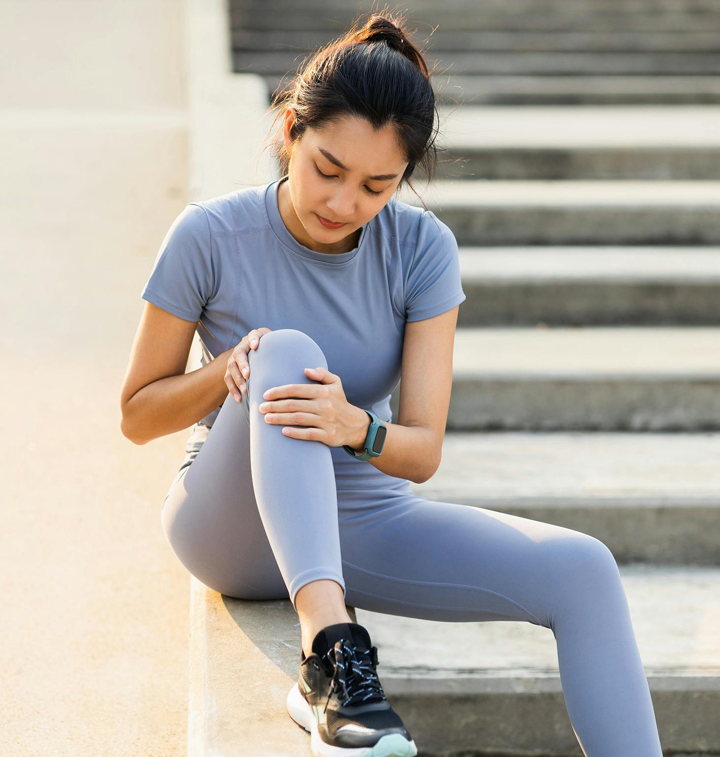 woman sitting on steps with her leg in pain