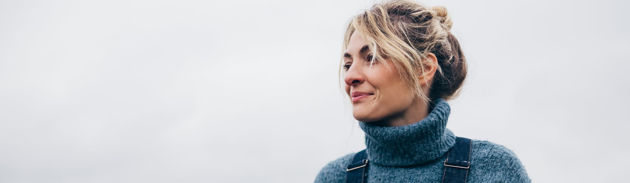 blond woman in a blue sweater and black bag looking away