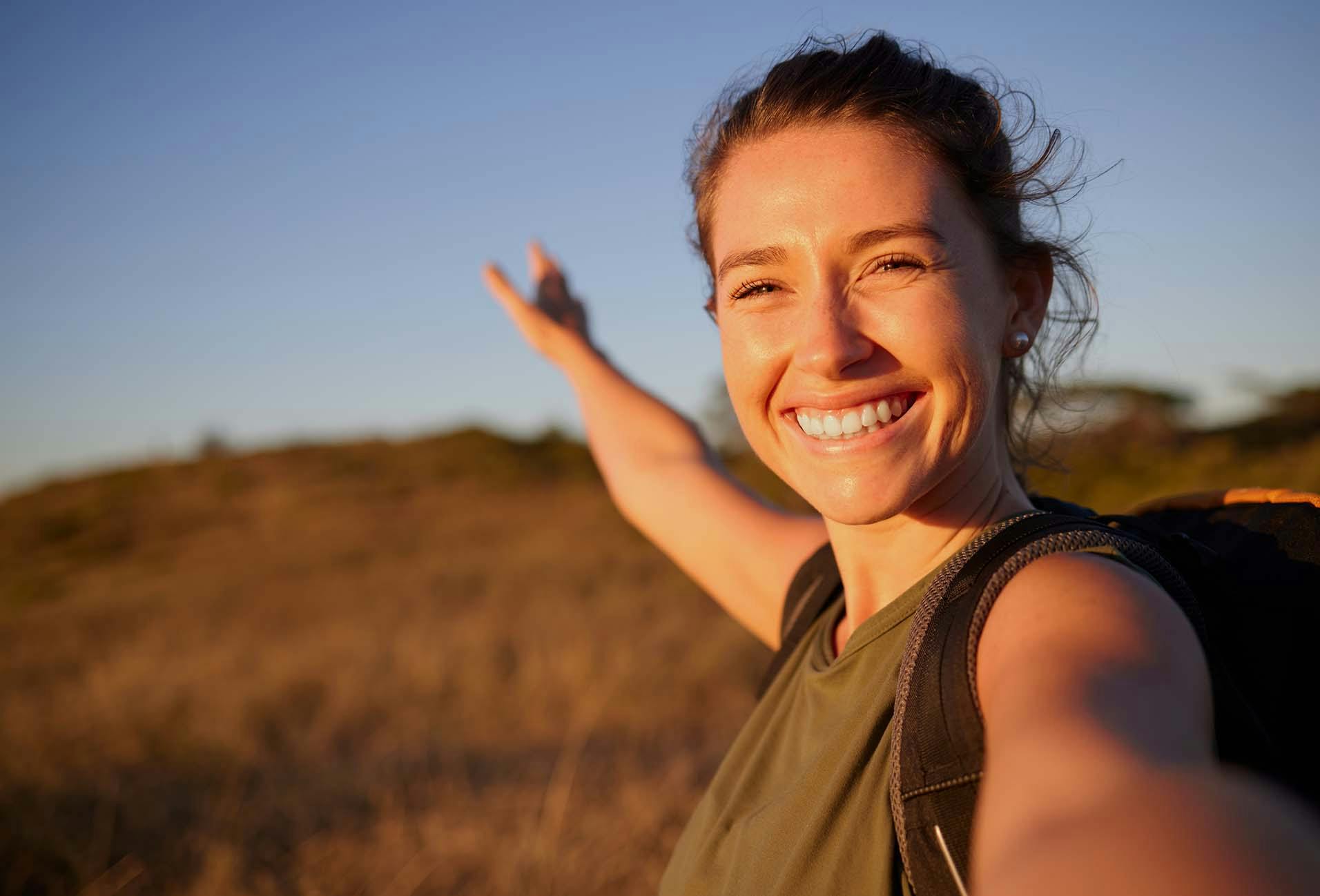 smiling woman with arms outstretched in a field of grass